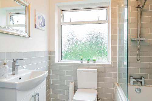 a bathroom with a toilet and a sink and a window at Stunning Place, close to Windsor & Heathrow & Private Parking in Burnham