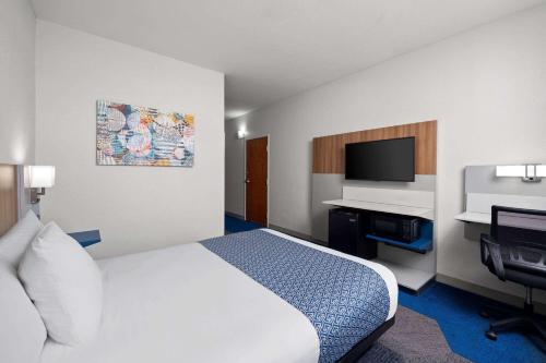 a hotel room with a bed and a flat screen tv at Microtel Inn & Suites by Wyndham of Houma in Houma
