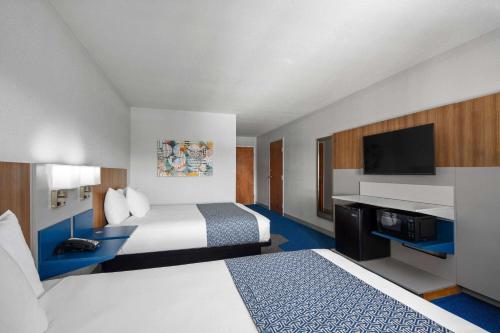 a hotel room with two beds and a flat screen tv at Microtel Inn & Suites by Wyndham of Houma in Houma