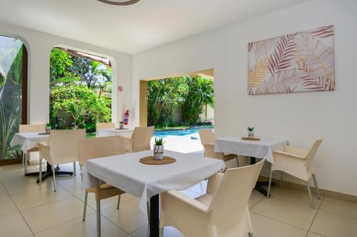 een restaurant met witte tafels en stoelen en een zwembad bij Caza Beach Guesthouse in Durban