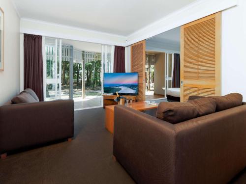 sala de estar con 2 sofás y TV de pantalla plana en Novotel Sunshine Coast Resort, en Twin Waters