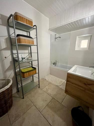 La salle de bains est pourvue d'une étagère à côté d'un lavabo et d'une baignoire. dans l'établissement LE SOUSTET, à Châteauneuf-du-Pape