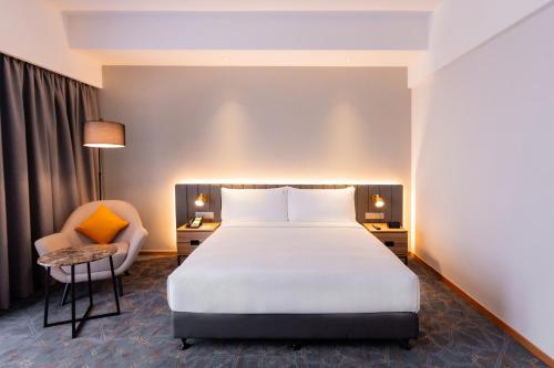 a hotel room with a bed and a chair at Holiday Inn Sepang - Airport in Sepang