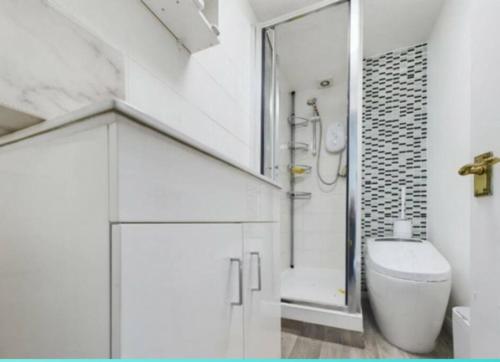 uma casa de banho branca com um chuveiro e um WC. em Central Brentwood House em Brentwood