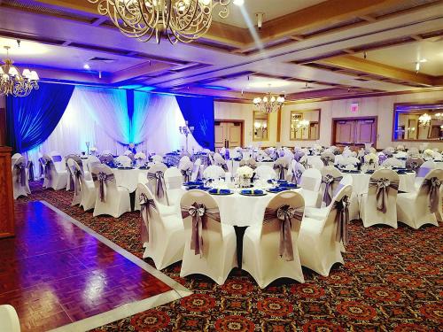 a banquet hall with white tables and chairs and a chandelier at Piccadilly Inn Airport in Fresno