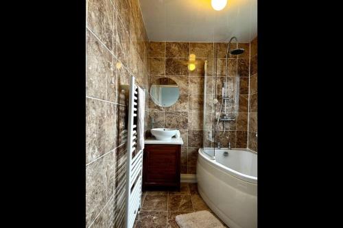 een badkamer met een bad, een wastafel en een bad bij A Stones Throw From The Beach! in Vickerstown
