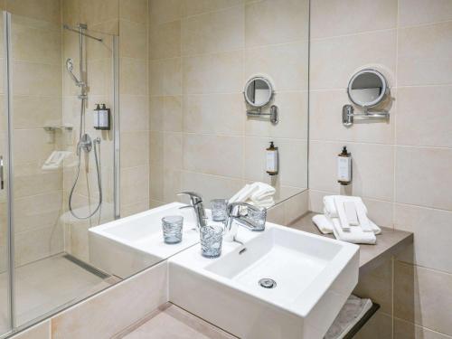 a white bathroom with a sink and a shower at Mercure Geneva Airport in Geneva