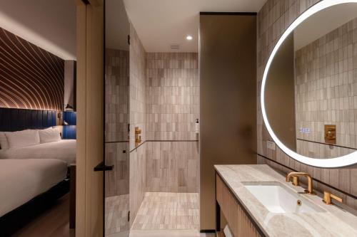 a bathroom with a bed and a sink and a mirror at Tempo By Hilton New York Times Square in New York