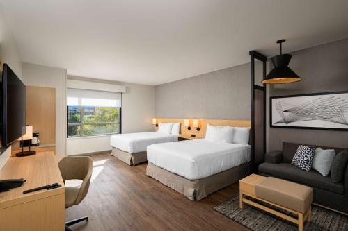アルバニーにあるHyatt Place Albanyのベッド2台とソファが備わるホテルルームです。