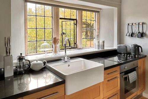 a kitchen with a sink and two windows at Cotswolds Place - Chancewell in Broadway