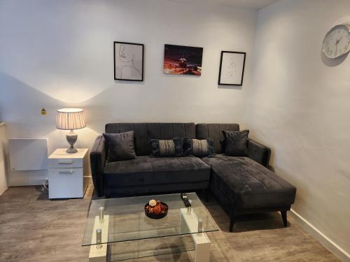 a living room with a couch and a clock on the wall at DD Apartment 2 - Free Parking - Fast WifI in Castle Donington