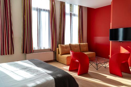 a bedroom with red walls and a bed and a chair at Hotel d'Alcantara in Tournai