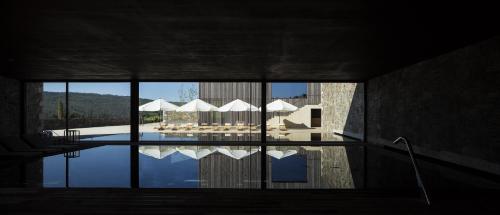 uma vista para uma piscina com mesas e guarda-sóis em Monverde - Wine Experience Hotel - by Unlock Hotels em Amarante
