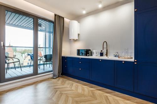 uma cozinha com armários azuis e uma grande janela em Apart ,,Centrum Stare Miasto ,, Widok na Motławę em Gdańsk