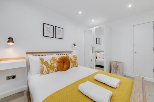 倫敦的住宿－Deluxe 1 Bed Flat - Shoreditch, Aldgate & The City of London，卧室配有白色大床和黄色及白色枕头