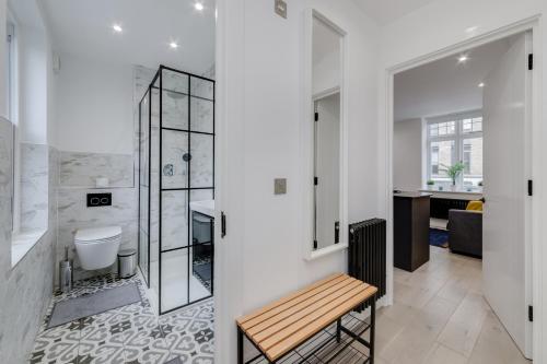a bathroom with a toilet and a sink and a bench at Deluxe 1 Bed Flat - Shoreditch, Aldgate & The City of London in London