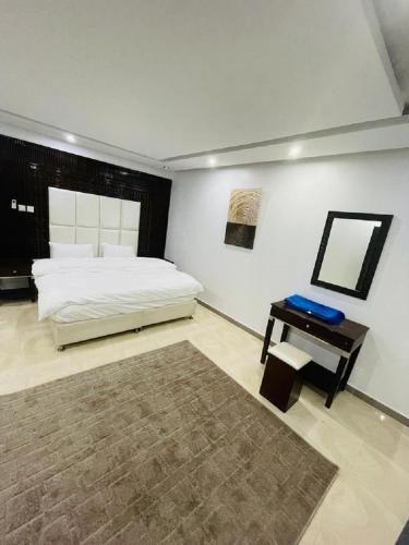 a bedroom with a bed and a table with a mirror at نخلة الصحراء للشقق المخدومة in Al Nairyah