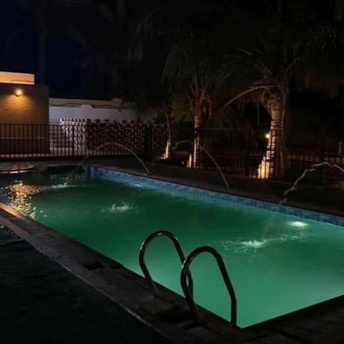a swimming pool with green water at night at The Holiday Farm in Barka