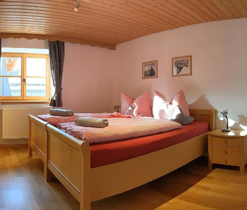 Schlafzimmer mit einem Bett mit roter Bettwäsche und weißen Kissen in der Unterkunft Ferienwohnung Mathias Kennerknecht in Fischen im Allgäu