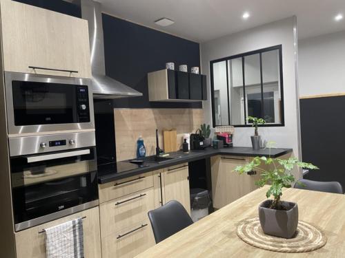 a kitchen with a table with a microwave and a stove at L’escale féerique in Auxerre