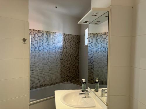 een badkamer met een wastafel en een spiegel bij La casa Marcel, maison de 110 m2 in Pia