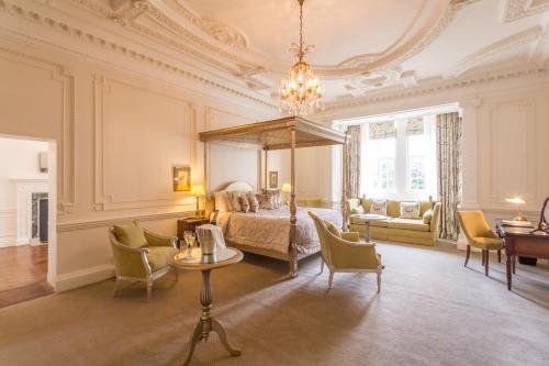 1 dormitorio con 1 cama, mesa y sillas en Rushton Hall Hotel and Spa en Kettering