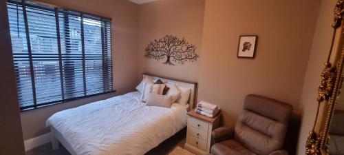 um quarto com uma cama, uma cadeira e um espelho em Spacious Home - King Size Bed - Pets - In Oak Hill em Trent Vale