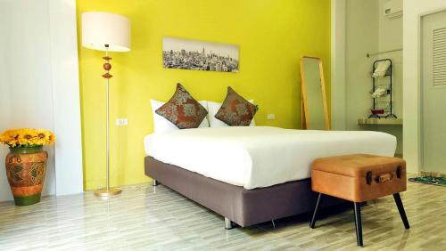 sypialnia z dużym białym łóżkiem i żółtą ścianą w obiekcie บ้านเพิงโฮมสเตย์ w mieście Ban Khuan Rai