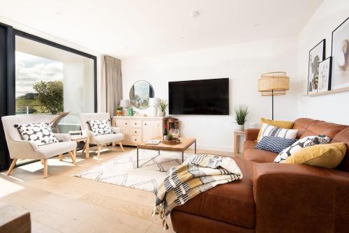 a living room with a brown couch and chairs at 6 The Bay in Coldingham