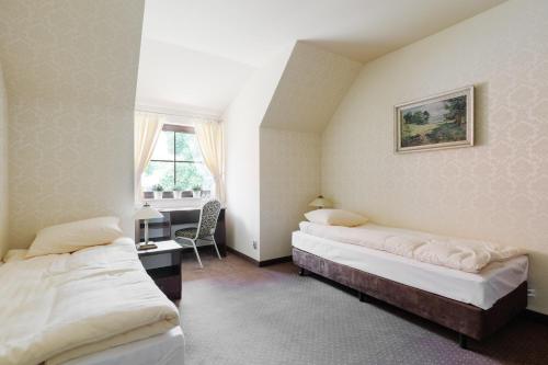 a bedroom with two beds and a desk and a window at Hotel Folwark in Zgierz