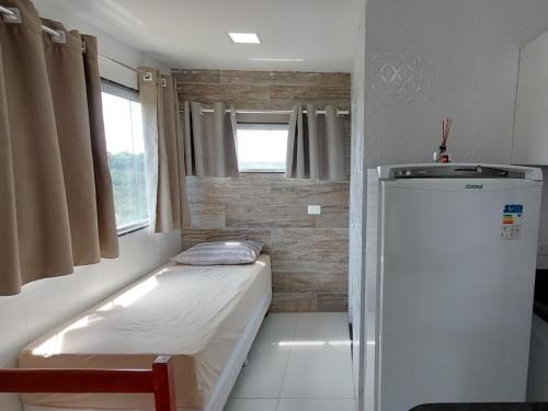 Habitación pequeña con cama y nevera. en Apartamentos Mobiliados, en Aldeia