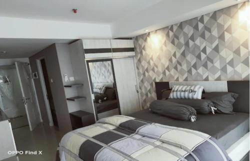 a bedroom with a large bed and a mirror at Apartemen Skylounge Makassar in Manda