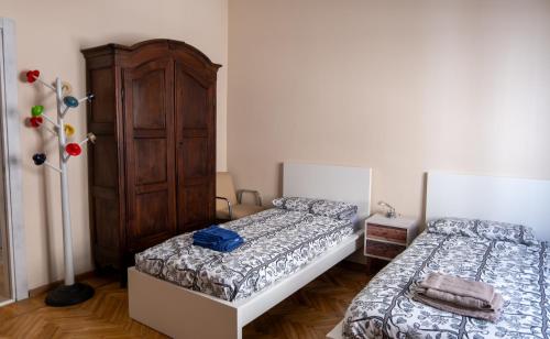 a bedroom with two beds and a wooden cabinet at CASA MIRELLA in Casale Monferrato