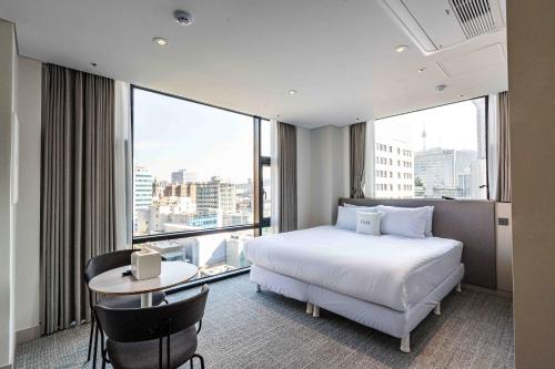 a bedroom with a bed and a desk and a large window at Hotel Vert in Seoul