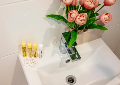 eine Vase rosa Rosen auf einem Waschbecken im Bad in der Unterkunft Welcome London Leicester Square in London