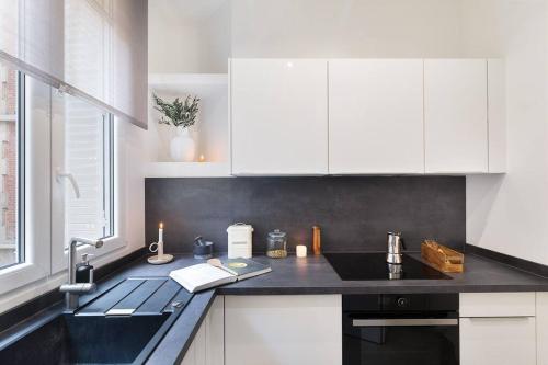 une cuisine avec des armoires blanches et un comptoir noir dans l'établissement Nocelle - 2 chambres à Batignolles, à Paris