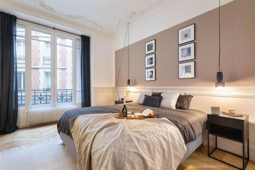 une chambre avec un grand lit et une grande fenêtre dans l'établissement Nocelle - 2 chambres à Batignolles, à Paris