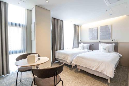 a hotel room with two beds and a table and chairs at Hotel Vert in Seoul