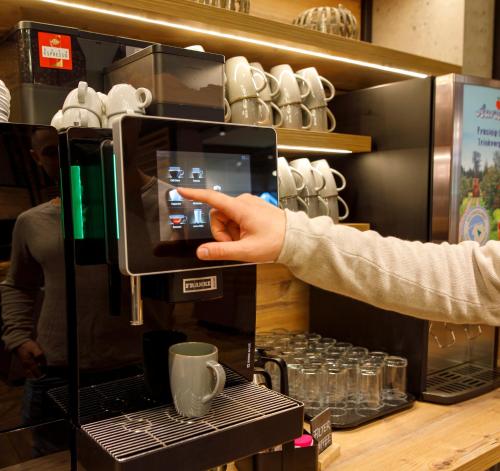 a person taking a picture of a coffee machine at Kedi Hotel Papenburg in Papenburg