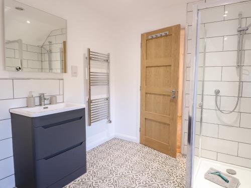 a bathroom with a sink and a shower and a door at Well Cottage in Norwich