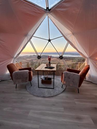 a tent with a table and chairs in a room with a view at Forbord Dome 