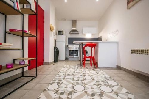une cuisine avec une chaise rouge au milieu d'une pièce dans l'établissement Logis des Barques YourHostHelper, à Narbonne