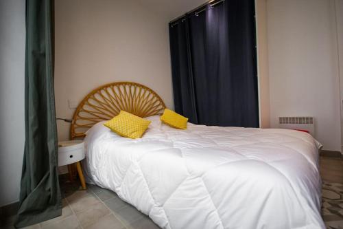 - une chambre dotée d'un lit blanc avec des oreillers jaunes dans l'établissement Logis des Barques YourHostHelper, à Narbonne