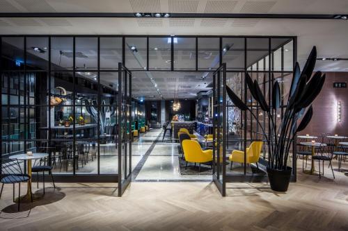 a restaurant with yellow chairs and tables and glass walls at Van der Valk Hotel Enschede in Enschede