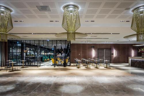 a lobby with tables and chairs and chandeliers at Van der Valk Hotel Enschede in Enschede