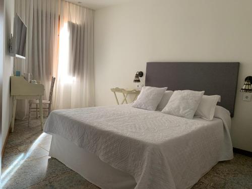 1 dormitorio blanco con 1 cama grande con sábanas blancas en Círculo Artístico 1911 Hotel Boutique, en Caravaca de la Cruz