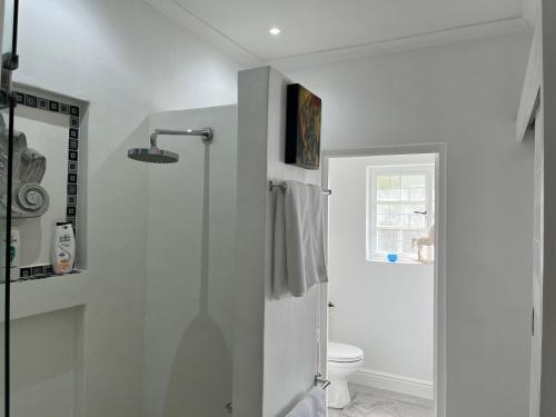 a white bathroom with a toilet and a window at Somerset West Garden Apartments 2 in Somerset West