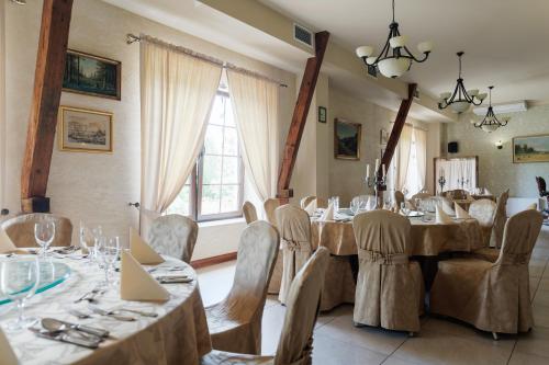 a dining room with tables and chairs and a window at Hotel Folwark in Zgierz