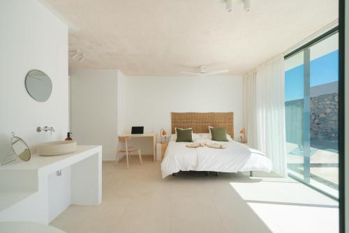 a white bedroom with a bed and a desk at Areté in Mácher