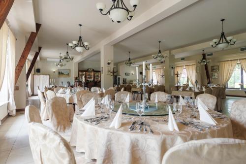 un salón de banquetes con mesas y sillas blancas en Hotel Folwark en Zgierz